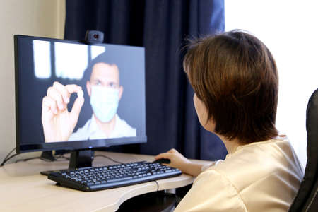 Online consultation with a doctor, woman listens to the doctor recommendations sitting in front of...