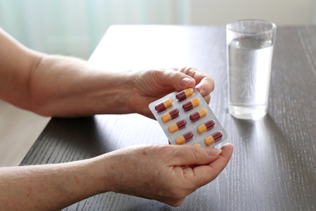 Pills in hands of elderly woman. Medication in capsules, taking sedatives or vitamins