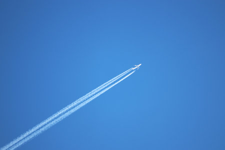Jet airplane with white contrail. Trace of the high flying plane on the blue skyの写真素材