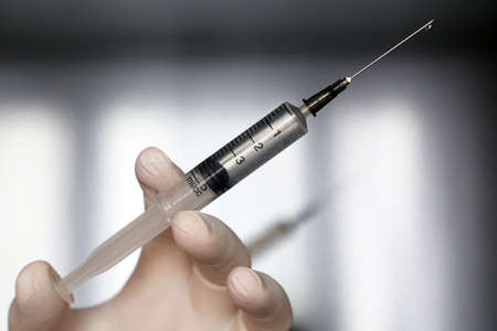 Syringe in hand close up, doctor in protective gloves preparing to injection. Concept of vaccination during   pandemicの写真素材
