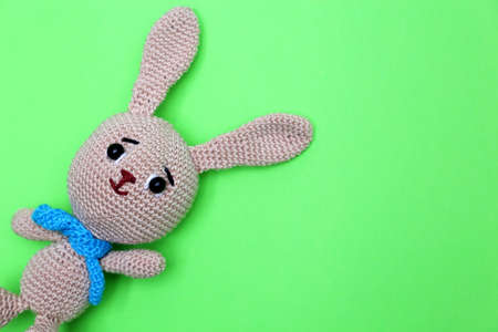 Easter Bunny on green background. Greeting card with knitted toy rabbit with free copy spaceの写真素材