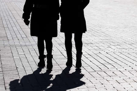 Silhouettes and shadows of two women walking down the street. Concept of female friendshipの写真素材