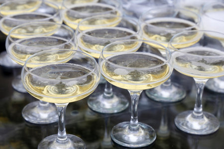 Glasses with white sparkling wine, champagne are reflected in glass table. Concept of celebration, evening partyの写真素材