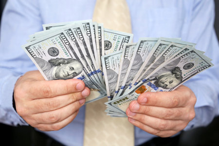 US dollars in male hand close up, man in business clothes with money. Concept of bribe, salary, success, financial assistance or loanの写真素材
