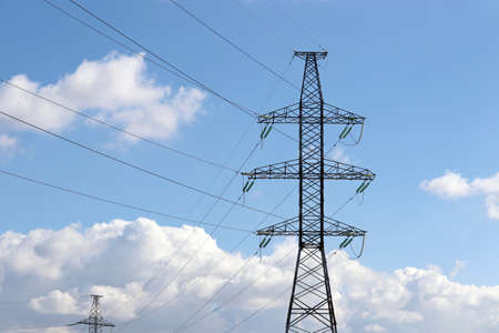 High voltage towers with electrical wires on blue sky with white clouds. Electricity transmission...