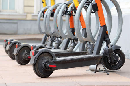 Electric scooters in a row on the parking lot. City bike rental system, public e-scooters on the...