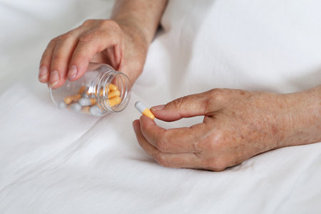 Elderly woman with pills in wrinkled hands. Medication in capsules, taking sedatives, antibiotics or vitaminsの写真素材