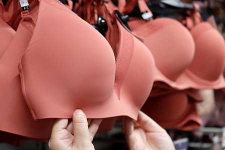 Seamless bra hanging on rack in lingerie store. Woman chooses sexy underwearの写真素材