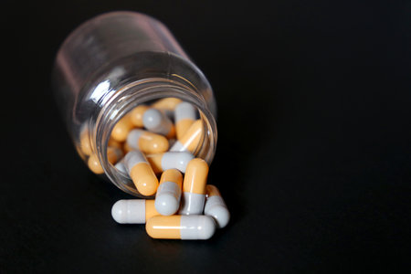Pills on black background, bottle of medication in capsules. Concept of nutritional supplements,...