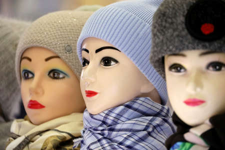 Female warm knitted hats and neckerchiefs on mannequins. Winter clothing store, woolen caps on saleの写真素材