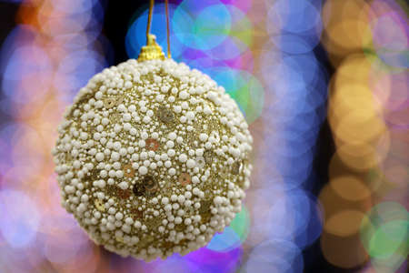 Christmas toy ball on blurred lights background. New Year decorations and festive illuminationの写真素材