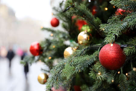 New Year decorations on a city street. Christmas tree with red and golden toy balls on blurred...
