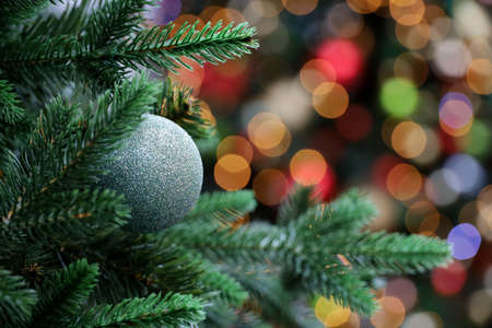 Christmas toy ball on blurred lights background. New Year tree with bauble, festive decorationsの写真素材