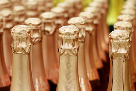 Sparkling wine bottles in golden foil for New Year celebration. Champagne in wine store, alcohol industryの写真素材