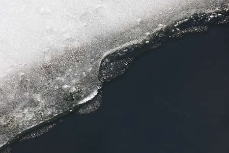 Melting ice on the lake. Ice edge on the frozen shore, early spring season