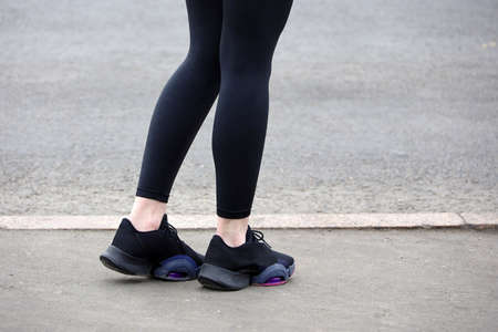 Female legs in sneakers and leggings on asphalt, slim girl runner on a street. Concept of spring...