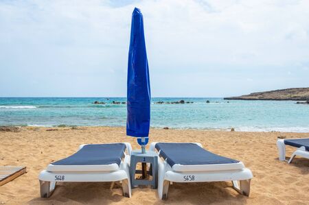 Umbrellas and sun beds on the sandy beach at the beginning of the season. Empty beach. Deserted recreation areas. Ayia NAPA, Cyprusの写真素材