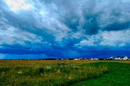 Stormy sky on a summer day over a blooming field. Idyllic farmland with lush fields in a magnificent...