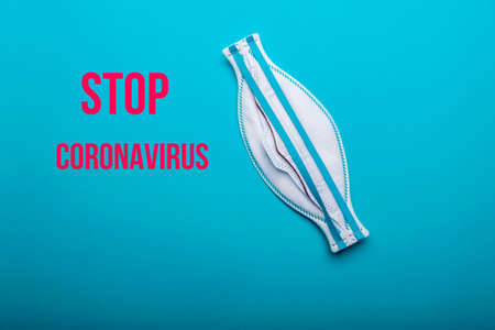 Protective mask with the inscription stop coronavirus. Protective mask against a coronavirus outbreak on a blue background. Inscription to stop the coronavirus.の写真素材