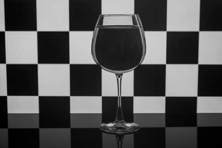 An empty wine glass stands against a chessboard. Concept.の写真素材