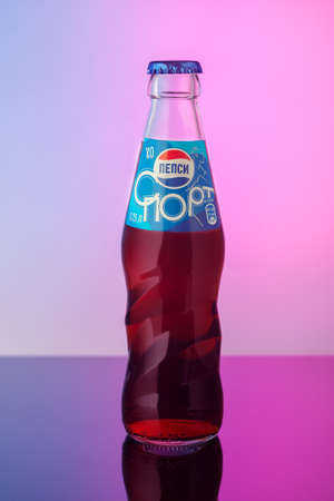Classic glass bottle of soft drink Pepsi-Cola, on a blue-pink background. American multinational food and beverage company PepsiCo. Moscow, Russia-March 2020.のeditorial素材