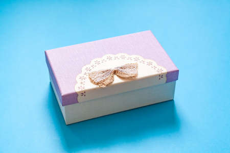 cardboard gift box in purple color scheme with a bow on a blue backgroundの写真素材