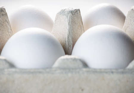 Chicken eggs with a white shell in a cardboard box on a white background