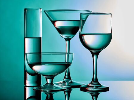 Different glass goblets on a turquoise background. Beautiful still lifeの写真素材