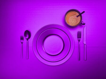 A cup of coffee with purple plates, a fork, a knife and a spoon, top view. Ceramic dishes with a set of cutlery. Empty purple tableware for breakfast or dinner in a restaurant. Copyspace for your individual text.の写真素材