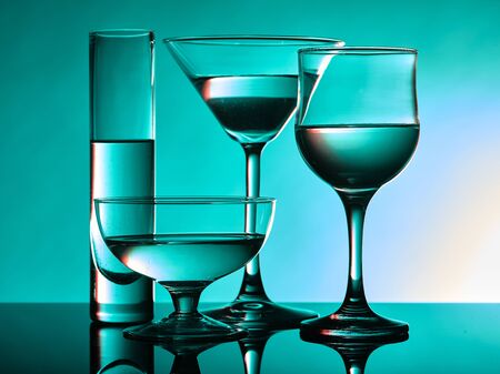 Different glass goblets on a turquoise background. Beautiful still lifeの写真素材