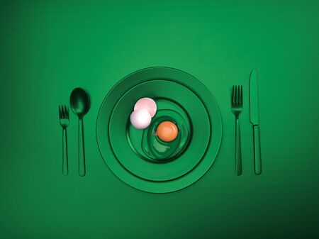 Green dishes with a broken egg and shell on a plate. Ceramic dishes with a fork, spoon and knife. For cafes, posters, breakfasts and dinners. Copyspace for your individual textの写真素材