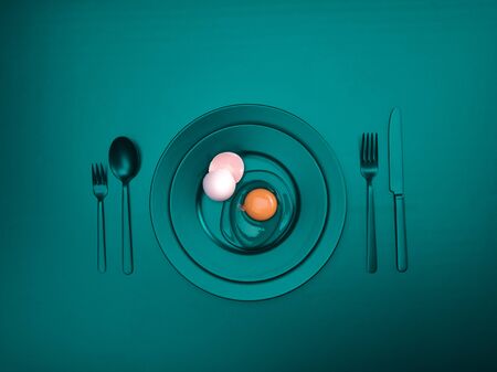 Turquoise dishes with a broken egg and shell on a plate. Ceramic dishes with a fork, spoon and knife. For cafes, posters, breakfasts and dinners. Copyspace for your individual textの写真素材