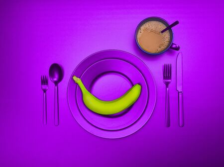 Purple dishes with banana on a plate. Cup of coffee with ceramic utensils with a fork, spoon and knife. For cafes, vegans, breakfasts and dinners. Copyspace for your individual textの写真素材