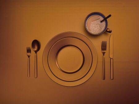 Cup of coffee with brown plates, fork, knife and spoon, top view. Ceramic dishes with a set of cutlery. Empty brown dishes for breakfast or dinner in a restaurant. Copyspace for your individual text.の写真素材