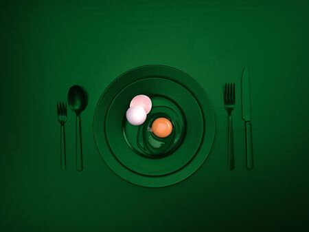 Green dishes with a broken egg and shell on a plate. Ceramic dishes with a fork, spoon and knife. For cafes, posters, breakfasts and dinners. Copyspace for your individual textの写真素材