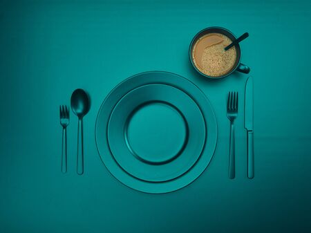 Cup of coffee with sea wave color plates, fork, knife and spoon, top view. Ceramic dishes with a set of cutlery. Empty sea wave color tableware for breakfast or dinner in a restaurant. Copyspace for your individual text.の写真素材