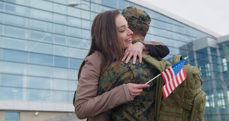Happy wife meeting his military husband after returning from military service. Young patriotic girl running and cuddling to his boyfriend in military uniform.Concept of military serviceの写真素材