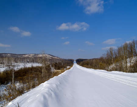 Winter landscape with road and woodの写真素材
