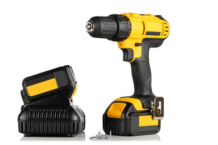 Handheld cordless power drill, battery, battery charger, screws on a white background.の写真素材