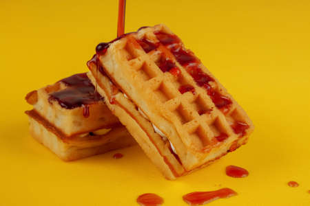 Soft waffles with filling on a yellow background cherry syrup