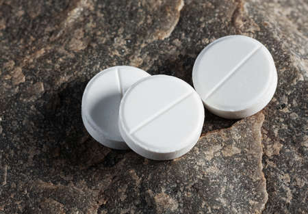 Three white pills close up on a stone backgroundの写真素材