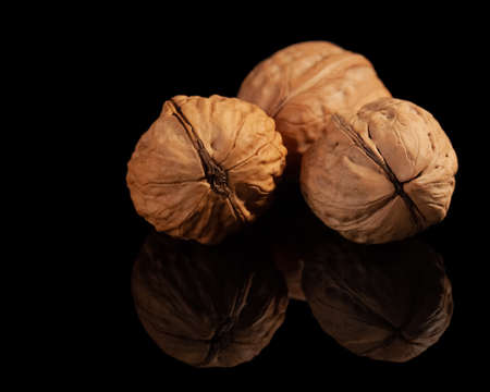 Ripe walnuts on a black background with reflectionの写真素材