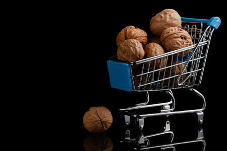 Walnuts in a toy grocery cart on a black background
