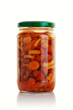A glass jar with pickled mushrooms on a white background.の写真素材