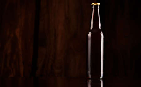 Glass brown beer bottle on the background of a wooden wallの写真素材