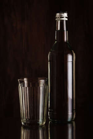 Faceted glass and a bottle of vodka on a dark backgroundの写真素材