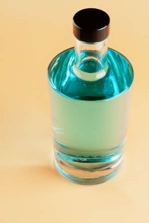 A bottle of blue gin on a light colored background