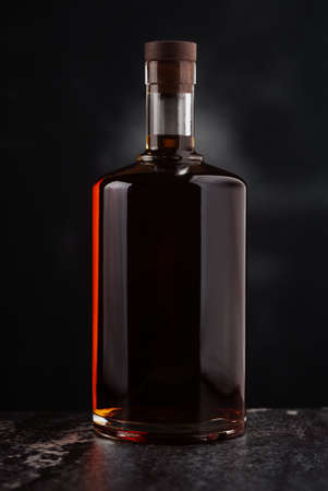 A full, closed brandy bottle on a dark backgroundの写真素材