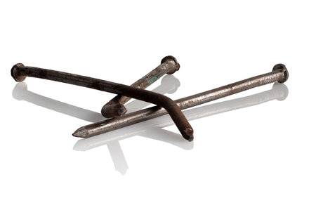 Three old, rusty, bent nails on a white backgroundの写真素材