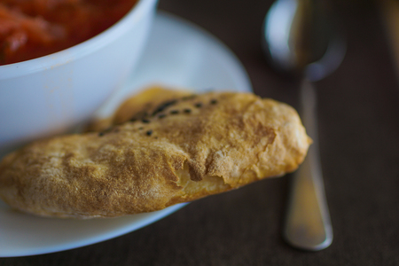 soup in a white plate with baked cake on gray background